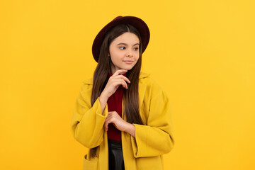 Poster - happy teen girl in hat and coat posing for photo on yellow background, autumn fashion