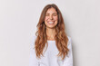 © WHstudio Leushin N - Portrait of good looking European woman smiles broadly with perfect even teeth has long wavy hair dressed in casual jumper isolated over white studio background. Authentic human emotions concept.