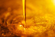 Orange liquid and viscous stream of motor oil close-up.