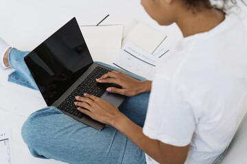 Young afro american woman working on laptop with blank screen