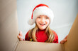© Анна Молько - surprised child opens a box with a Christmas present. cute baby wearing santa claus hat and red sweater