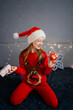 © Анна Молько - person in santa claus hat with gifts. cute child cheerfully jumping on the bed wearing a santa claus hat with gifts. home holiday christmas