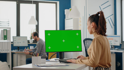 Poster - Woman working with isolated green screen on monitor at desk, looking at chroma key background with mock up template on display. Person using chroma-key on computer in business office