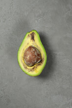 Half An Avocado With Darkening And A Stone. Close-up On A Gray Background.
