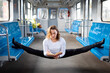 Flexible girl sitting on the split in subway and reading book. Concept of stretching and flexibility.