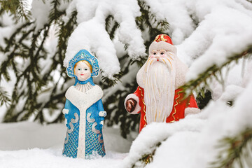 Wall Mural - Christmas decorations (Russian Santa Claus and Snow Maiden) standing under the snowy Christmas tree. New Year, holiday background.