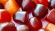 Selective focus.Close-up texture of red, orange and purple multivitamin gummies on white background