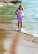 tween girl walking along the beach in a pretty dress