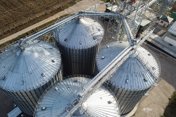 Agricultural facilities for grain storage and processing. Silver colored granaries at steep rural area. Silos storage tanks