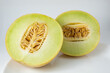 Ripe Gaul melon, cut in half with the seeds showing. Tropical fruit with white streaks on the yellow skin