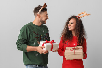 Wall Mural - Happy couple with Christmas gifts on light background