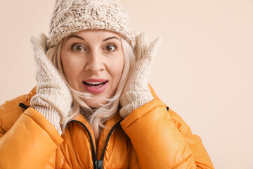 Poster - Surprised mature woman in winter clothes on color background