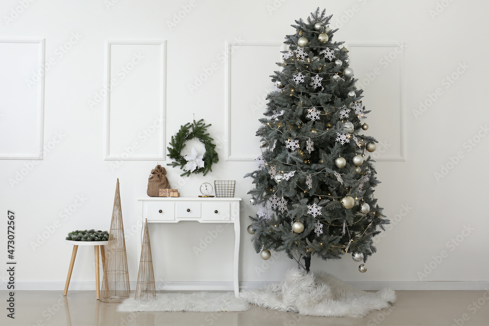 Interior of room with Christmas tree and decor near white wall