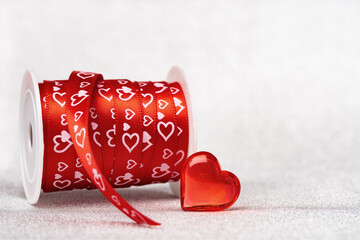 A roll of red gift ribbon with hearts for St Valentines day or 14 February. Glass heart. Minimal wide banner with copy space