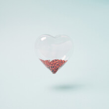 Transparent Heart Floating With Red Glitter Inside On Light Blue Background. Valentines Minimal Concept