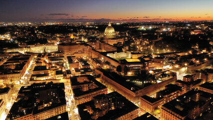 Wall Mural - Aerial drone night shot of iconic masterpiece Saint Peter Basilica and whole illuminated city of Vatican the biggest church in the world, Metropolitan city of Rome, Italy