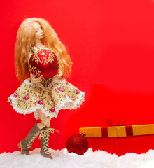 Wall Mural - girl doll with a Christmas ball in her hands and a New Year's gift on red