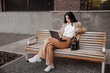 © Ankor_stock. - Young business woman sitting on a bench with a laptop of the modern office building background