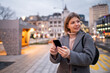 © bugarskipavle3 - Beautiful charming girl in coat standing in street and looking at telephone.Nice winter day.