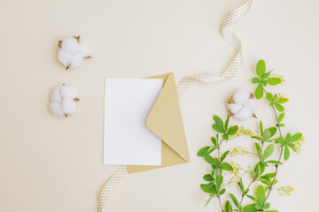 Wall Mural - mockup white wedding invitation and envelope with branches and green leaves on color background
