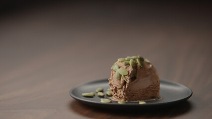 chocolate ice cream with pumpkin seeds on small saucer on wood table