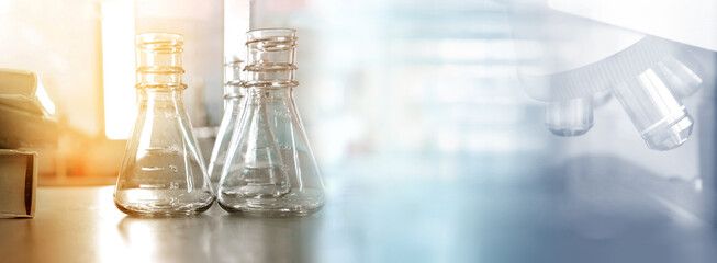 Wall Mural - flask and text book with microscope in health science lab education banner background