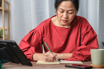 Poster - asian woman writing on notebook at working desk at home
