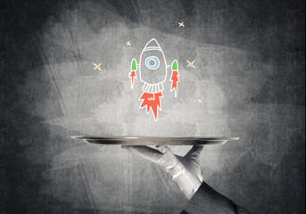 Wall Mural - Hand of waiter presenting sketched rocket on tray