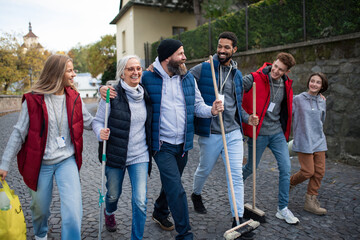 Wall Mural - Diverse group of happy volunteers walking with tools to do street clean up, community service concept