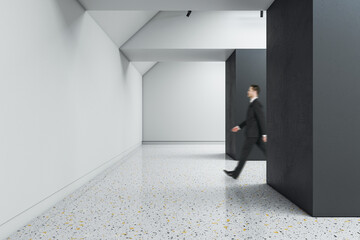 Poster - Businessman walking in creative concrete exhibition hall interior with daylight, mock up place. Gallery and museum concept.