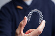 © l_martinez - Man holding one transparent aligner. Invisalign orthodontics concept