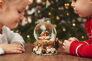 Children looking at a glass ball with a scene of the birth of Jesus Christ