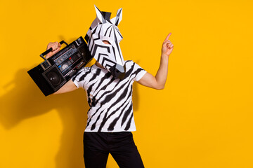 Poster - Photo of cool eccentric man wear zebra print t-shirt mask listening boombox pointing empty space isolated yellow color background