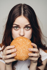 Wall Mural - woman with a hamburger in her hands a snack fast food close-up