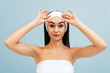 © _KUBE_ - Portrait of woman in a headband and a bath towel pulls her eyebrows with her hands. White markings above the forehead. The concept of massage and plastic surgery