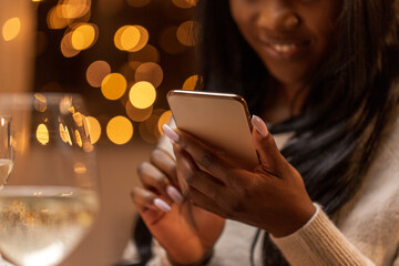 Poster - technology, holidays and celebration concept - close up of happy woman with smartphone at christmas dinner party