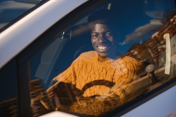 Wall Mural - Handsome young African American man in his new high-tech electric vehicle while drinking. Self driving vehicle concept