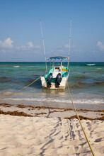 A Fishing Boat Anchored At The Edge Of The Water, On The Beach 