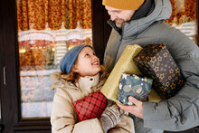 Father And Daughter Holding Christmas Presents In Front Of Store