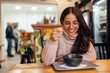 © bnenin - Smiling adult woman, with glasses, waiting for her food to cool.