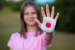 © Svetlana - Kid girl show stop gesture with hands painted in Japan flag colors. Reopen school, Healthcare. Education abroad. Learn Japanese. Selective focus