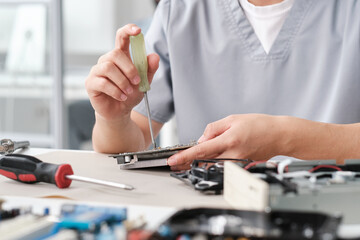 Poster - Hands of female troubleshooting technician fixing tiny details of computer hardware while sitting by workplace