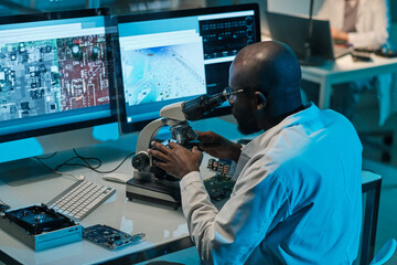 Aufkleber - Contemporary young African scientist with microscope working in front of computer monitors