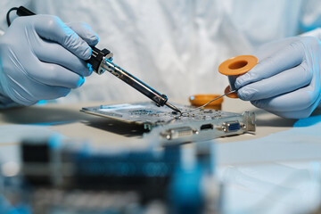 Poster - Gloved hands of repairman with soldering iron and tin repairing motherboard of computer