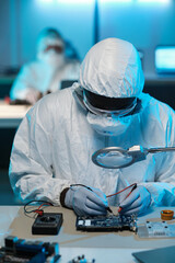 Poster - Contemporary repairman in protective workwear soldering circuit board while looking in magnifying glass