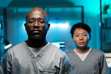 Poster - Two young intercultural researchers in uniform looking at camera while standing in laboratory