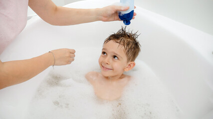 Wall Mural - Mother applying shampoo and washing head of her son in bath. Concept of hygine, children development and fun at home