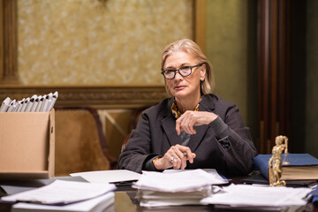 Aufkleber - Contemporary lawyer in eyeglasses and formalwear sitting by workplace and looking at camera while working with papers