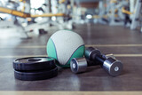 Metal dumbbells, barbell discs and medicine ball on the gym floor. Fitness, bodybuilding and functional training equipment