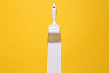 Paint brush with white stripe on a yellow background. Minimal layout. Top view